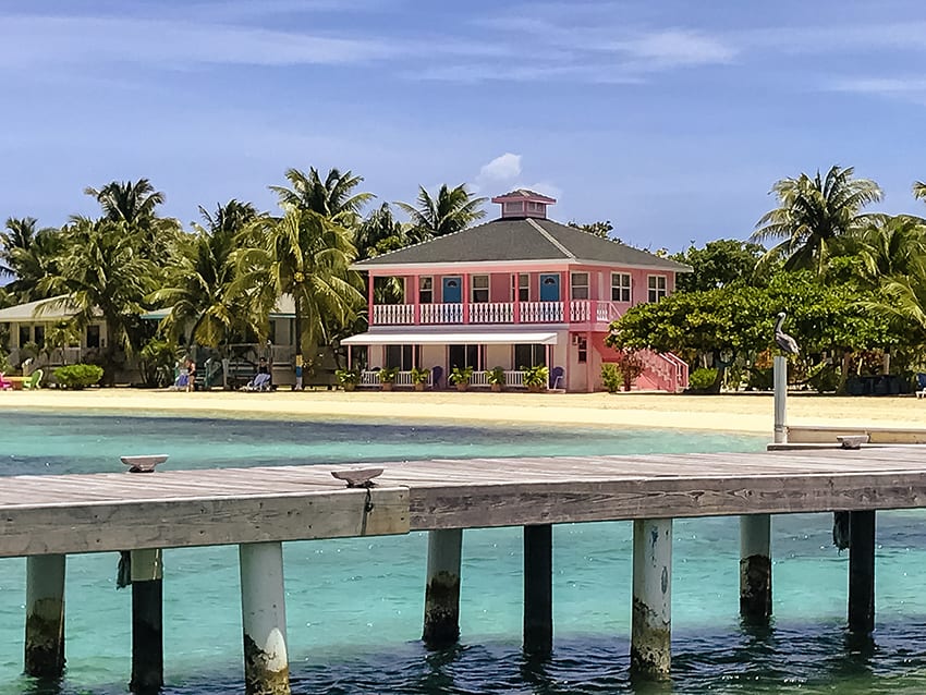 Graham's Place in Guanaja with candy pink house, palm trees white beach