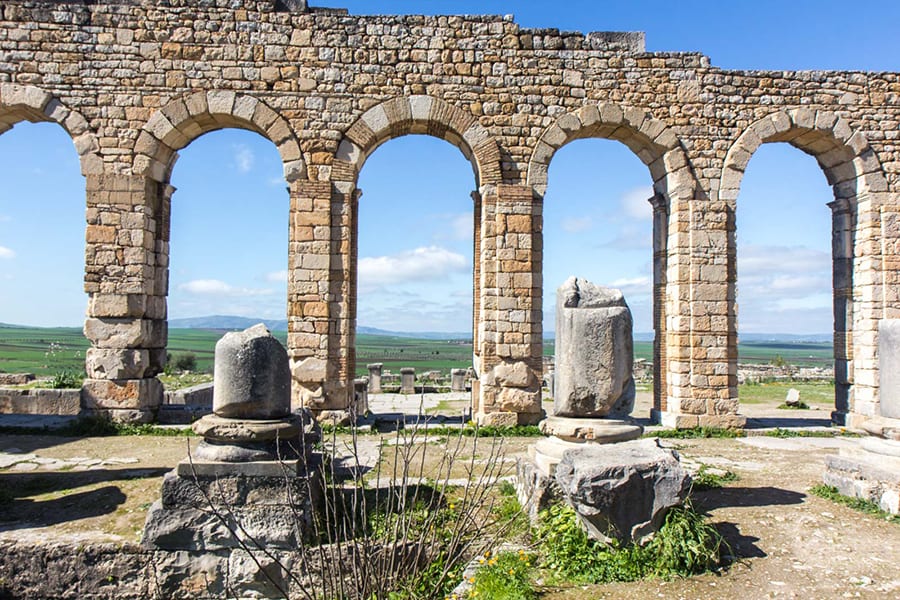 12 Amazing Unesco Heritage Sites In Africa 7 five arches made of sand coloured brick with a view of distant green fields and hills in the background and ruined pillars in the foreground