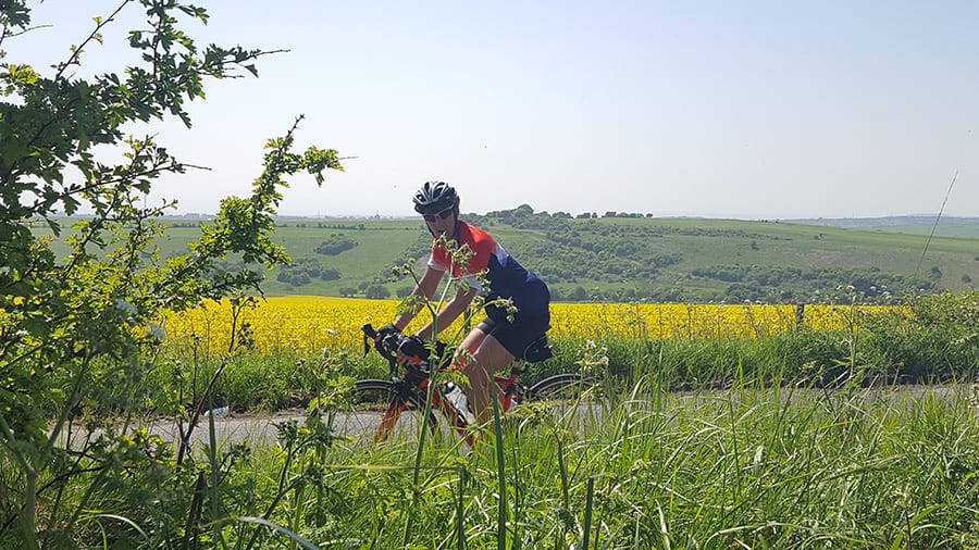 Guide to 17 Amazing UNESCO Heritage Sites in the UK 17 lady on bicycle wearing a crash helmet and cycling on a road through green fields and yellow rape fields