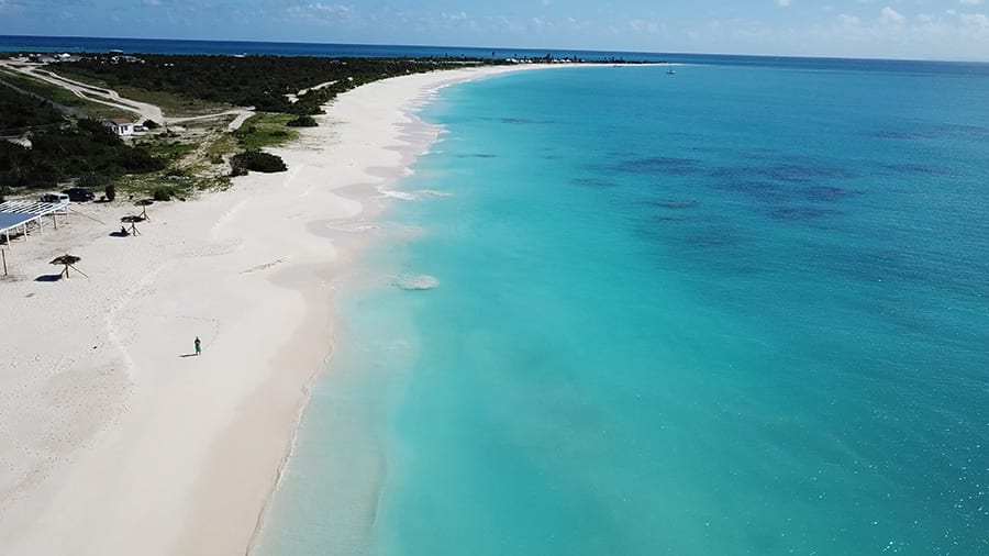 Barbuda – What you Need to Know Before You Go 7 Long white sandy beach on the island of Barbuda with turquoise sea on the right and green land to the left