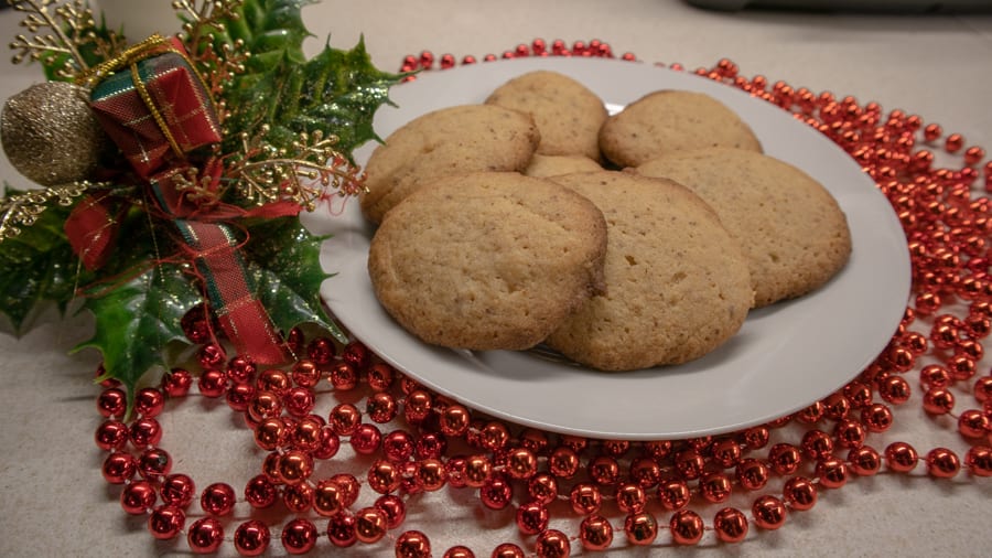 white plate with round biscuits surrounded by red shiny beads and holly with a tartan bow.