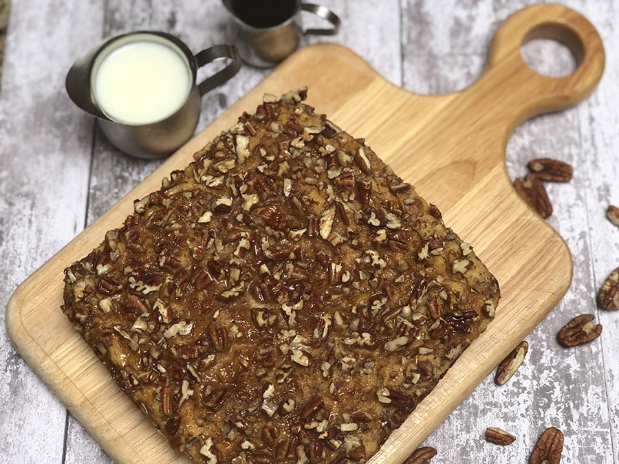 wooden board with square of brown french toast covered in pecans with pecans around - Chef Denise's Favourite Christmas bake for Breakfast