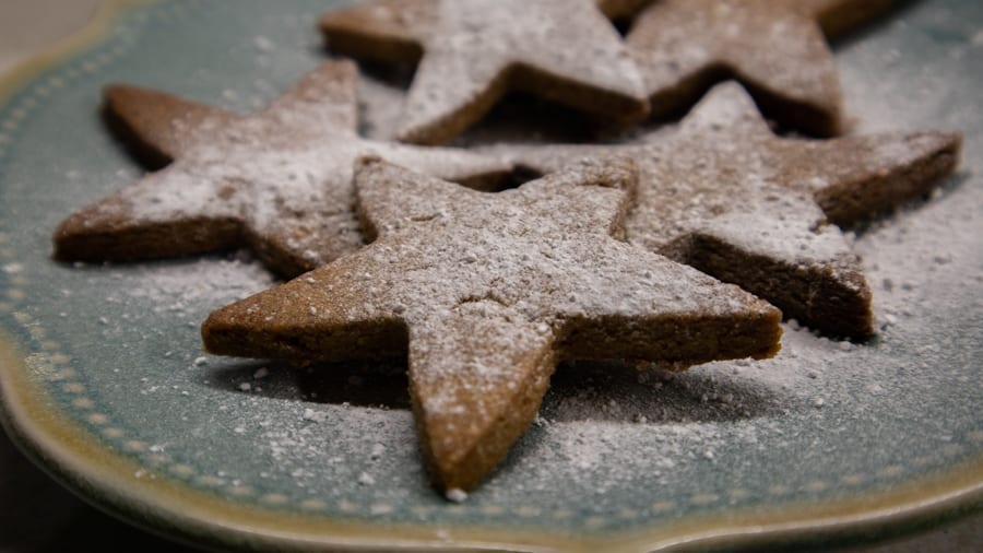 blue plate with star-shaped Dutch Christmas biscuits dusted with icing sugar