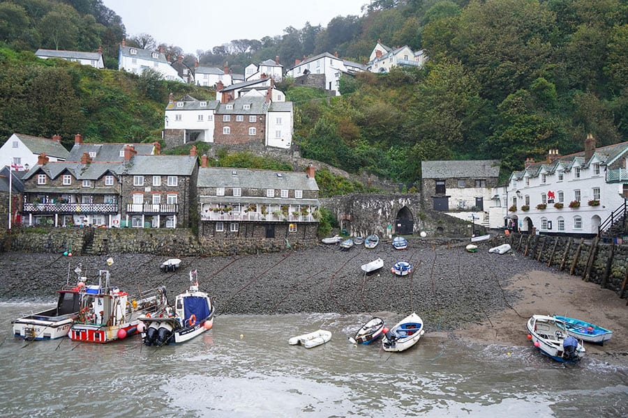 10+ of the Best Weekends in Devon 6 View from the sea of Clovelly. Boats tied up on long ropes with a dark beach and houses going up the hill