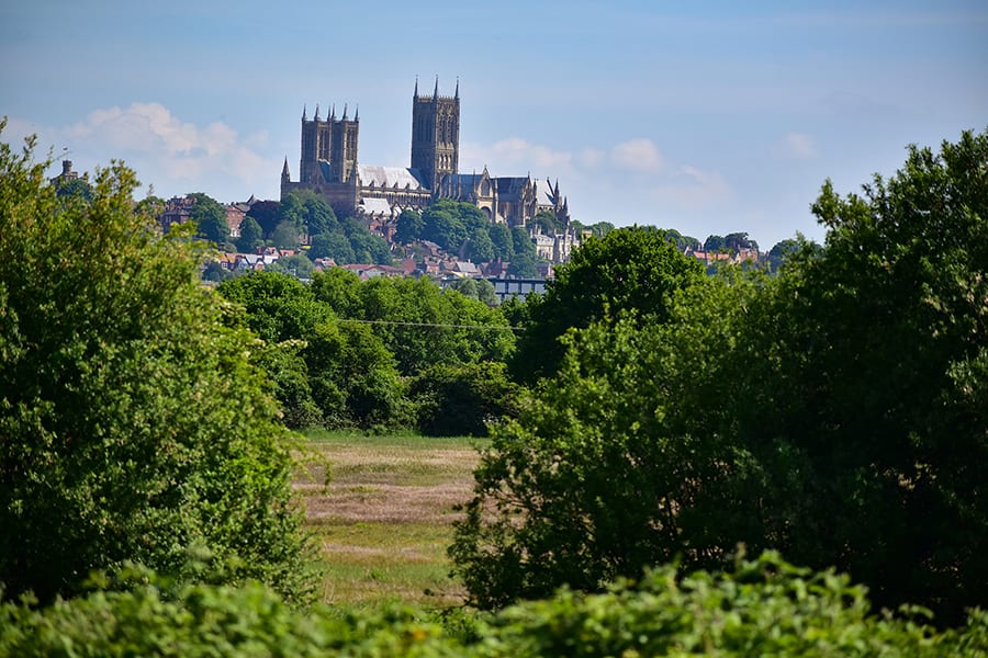 20+ of the Best Staycations in England 6 Lincoln Cathedral across the fields with trees in the foreground