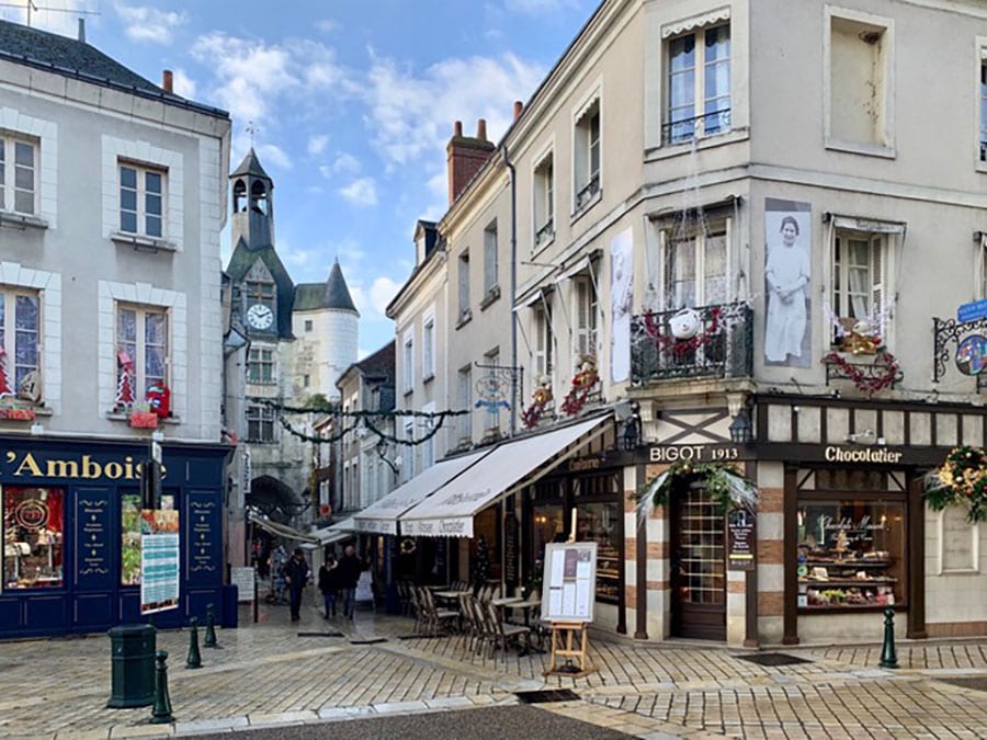 French town of Amboise with cobbled streets with shops and a church with turrets in the background