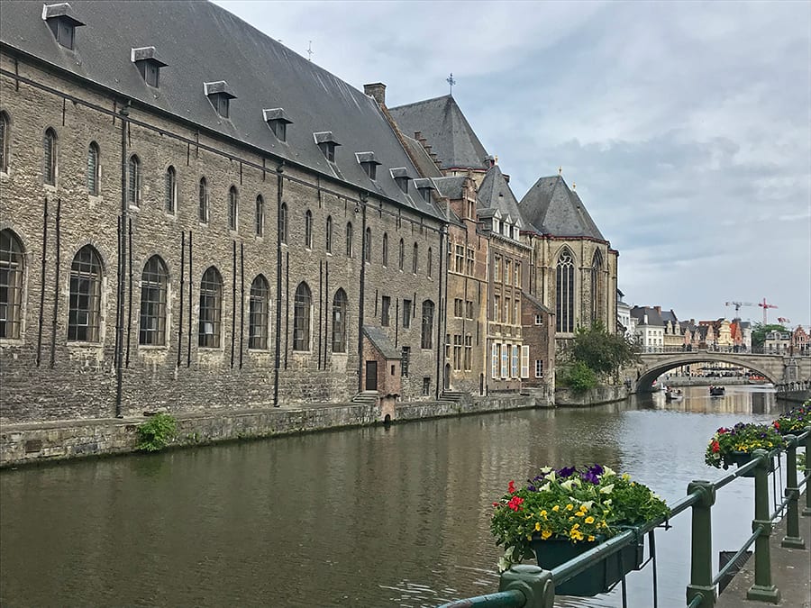 Canal with warehouses in Ghent with flowers baskets on the railings