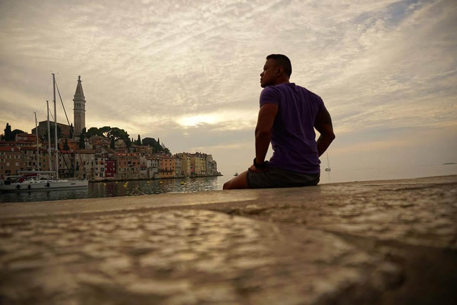 Man sitting on a dock looking out over the water towards Rovinj