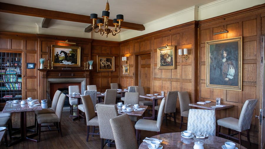 The Burleigh Court Hotel & Restaurant, Luxury in the Cotswolds 19 oak panelled restaurant with tables and chairs and paintings on the walls
