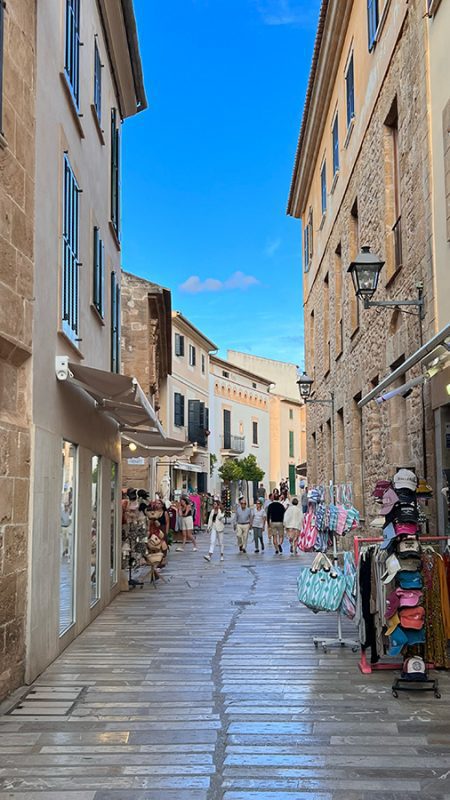 27 of the best things to do in Alcudia, Mallorca 2 Narrow street in Alcudia old town with shops to the sides selling bags, hats etc