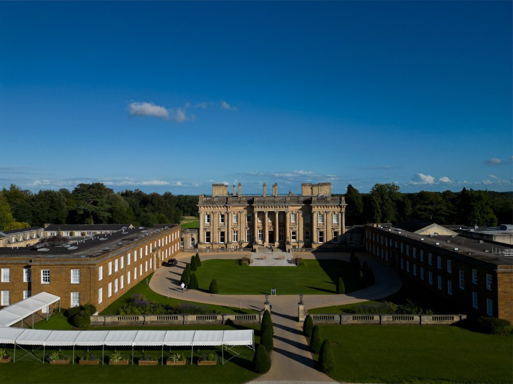 Heythrop Park by Warner Hotels, Luxury in the Cotswolds 2 The front of Heythrop Park in the Cotswolds, showing a grand golden stones Georgian building with four columns at the front. There are two wings, one on either side and a white covered walkway to the left