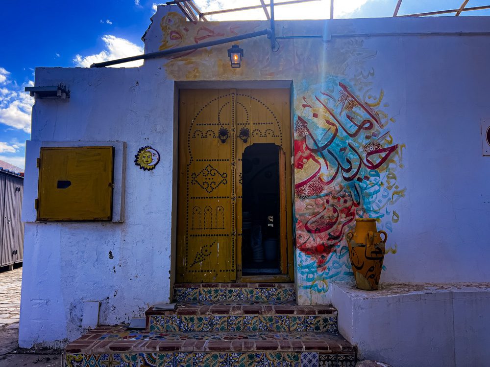 Sawa Taste Of Tunisia: Explore The Amazing Food Of Tunisia 10 The outside of Arceram with a yellow door studdied with black studs. Bright Arabic writing around the door