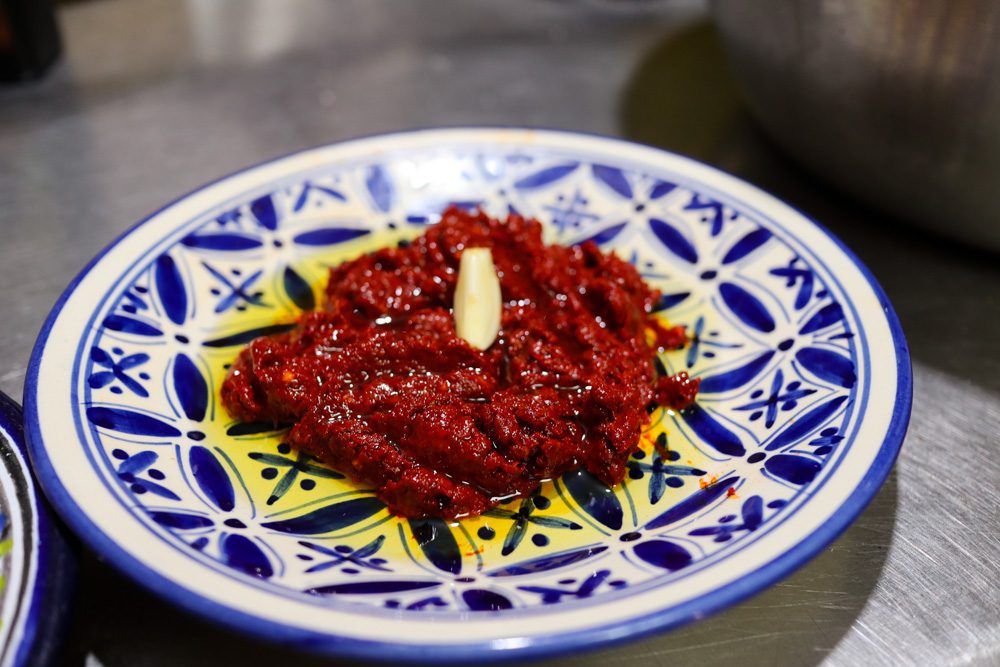 Sawa Taste Of Tunisia: Explore The Amazing Food Of Tunisia 8 the finished harissa with olive oil and garlic on a blue and white plate