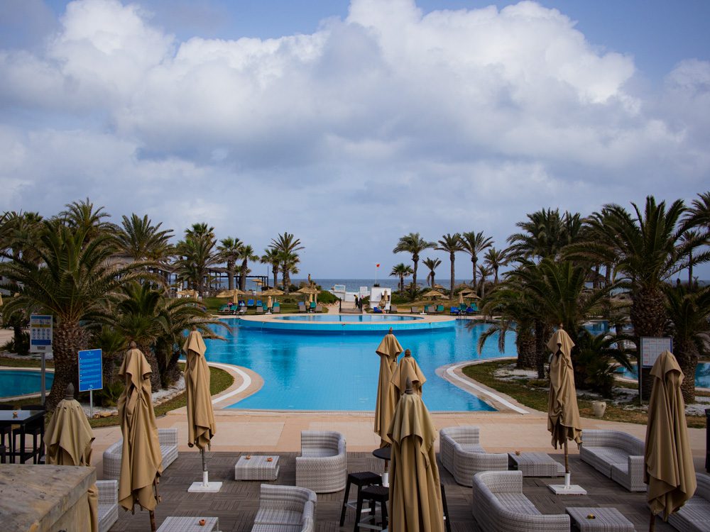 The Elegant VIP Suites at The Royal Thalassa Monastir 26 a pool with chairs and umbrellas and palm trees