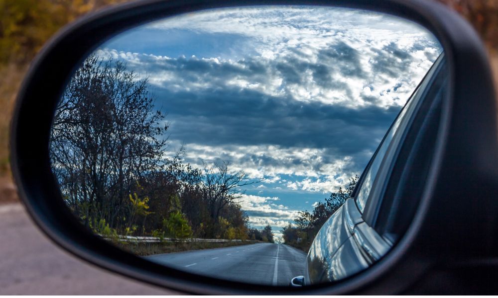 Must-Have Items For Your Ultimate Road Trip Adventure (2025) 10 rear view of road in a wing mirror