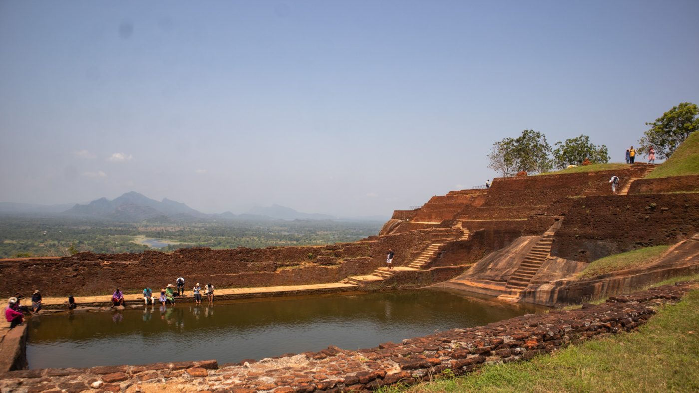Climbing The Amazing Lion Rock In Sigiriya: The Ultimate Guide (2025) 16 The swimming pool at the summit with people dipping their feet in with hills and jungle behind