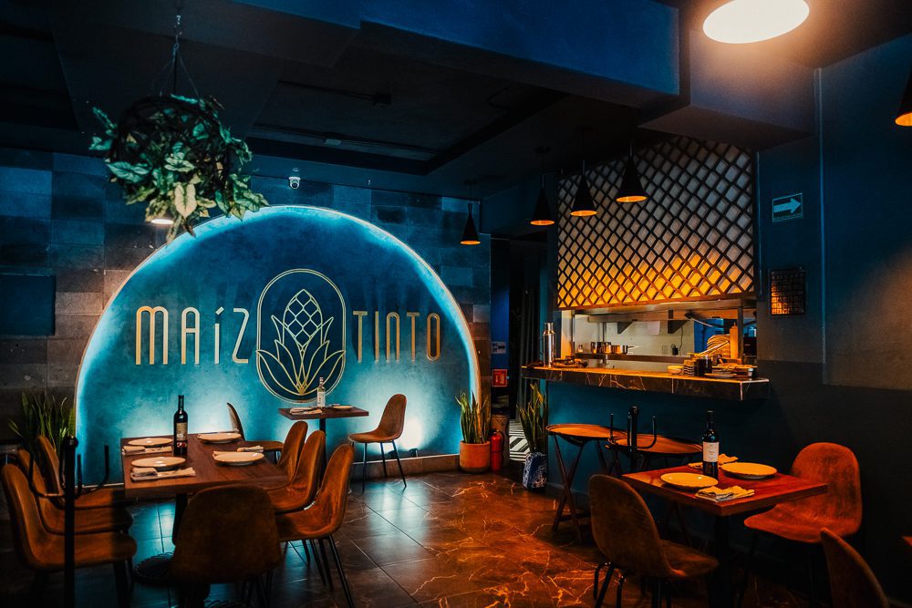 The Best Restaurants In Mexico City That Aren’t In The Usual Food Guides 5 Maiz Tinto one of the best restaurants in Mexico City showing tables set for dinner with roundbacked leather chairs and Maiz Tinto in large letters on the wall